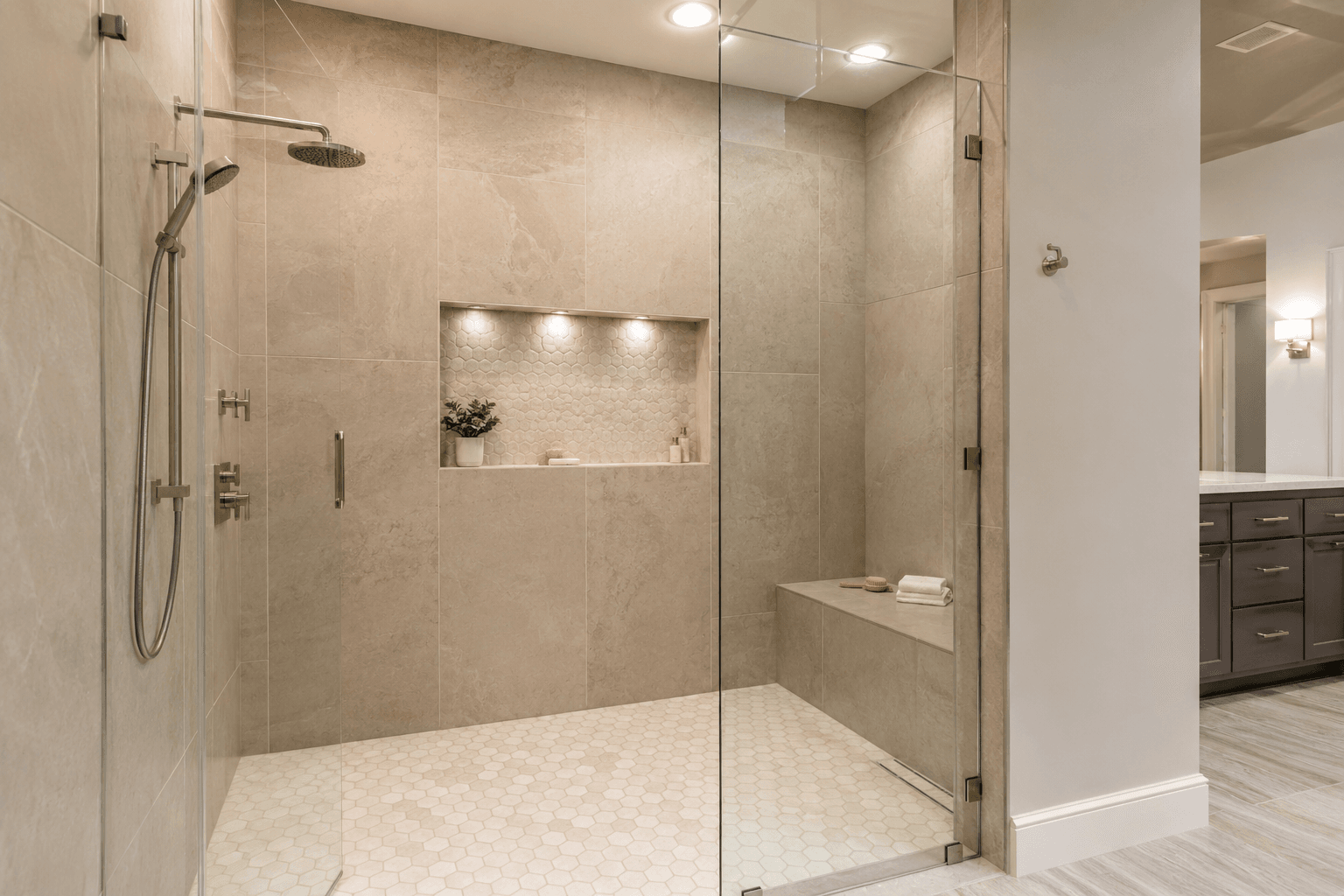 Modern walk-in shower with frameless glass, tiled walls, built-in niche, bench, and contemporary fixtures